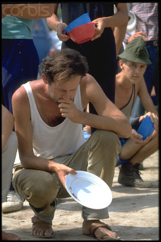 Bosnian Genocide, 1992: Emaciated Bosniak (Bosnian Muslim) man, posing for cameras, during a staged lunch at the Serb-run Trnopolje concentration camp near Prijedor, Bosnia, in August 1992. Thousands of prisoners, mostly Bosniaks (Bosnian Muslims), were tortured and killed there in 1992. Photographer: Patrick Robert